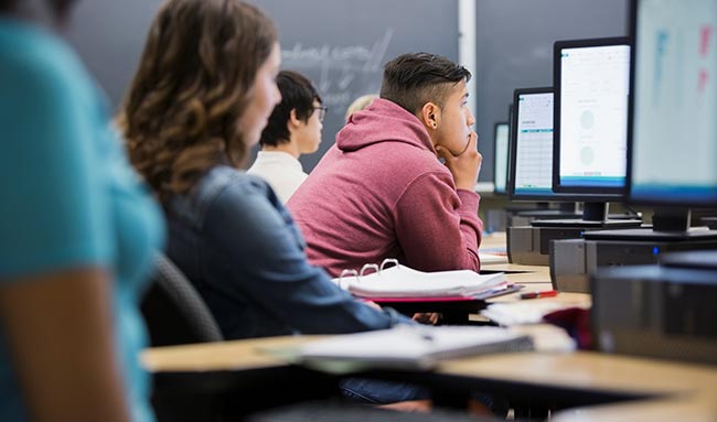 Students in class looking at desktop computers.